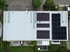Dach eines Gebäudes mit vielen schwarzen Solarmodulen und einem weißen Dach.