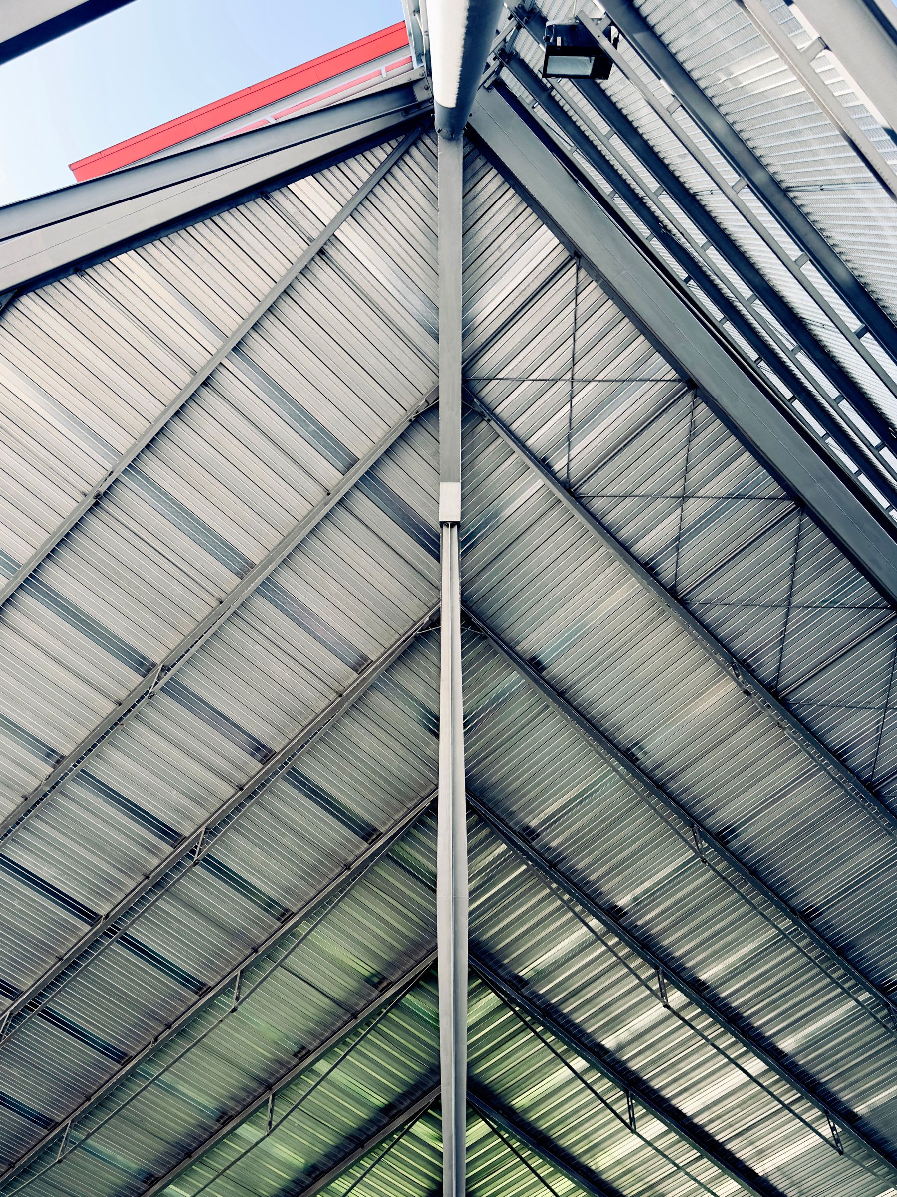 Standing seam metal roof panels meeting at a clean seam line against the sky