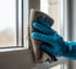 Nahaufnahme: Hand reinigt verschmutzten Fensterrahmen mit Tuch. Professionelle Fenster- und Fassadenreinigung in Wolfsburg und Braunschweig.