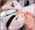 Eine Kosmetikerin behandelt das Gesicht eines Mannes mit einem Microneedling-Gerät.
