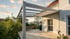 Moderne Terrassenüberdachung aus Aluminium mit Glasdach und ausziehbarer Markise an einem Haus.