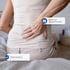 A woman stands and holds her lower back, experiencing sciatica.