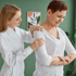 A female doctor gently assists a patient's shoulder during rehab.