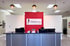 Reception desk at Hannigan Chiropractic and Rehab with a red accent wall, company logo, and three hanging globe lights.