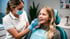 Eine lächelnde Zahnmedizinische Fachangestellte in Maske und Handschuhen untersucht die Zähne eines lächelnden jungen Mädchens.