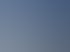 Ein Halo-Effekt mit mehreren konzentrischen Lichtringen um die Sonne über einer verschneiten Winterlandschaft mit Bäumen.