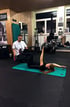 Ein Trainer hilft einer Frau bei einer Übung auf einer Fitnessmatte.