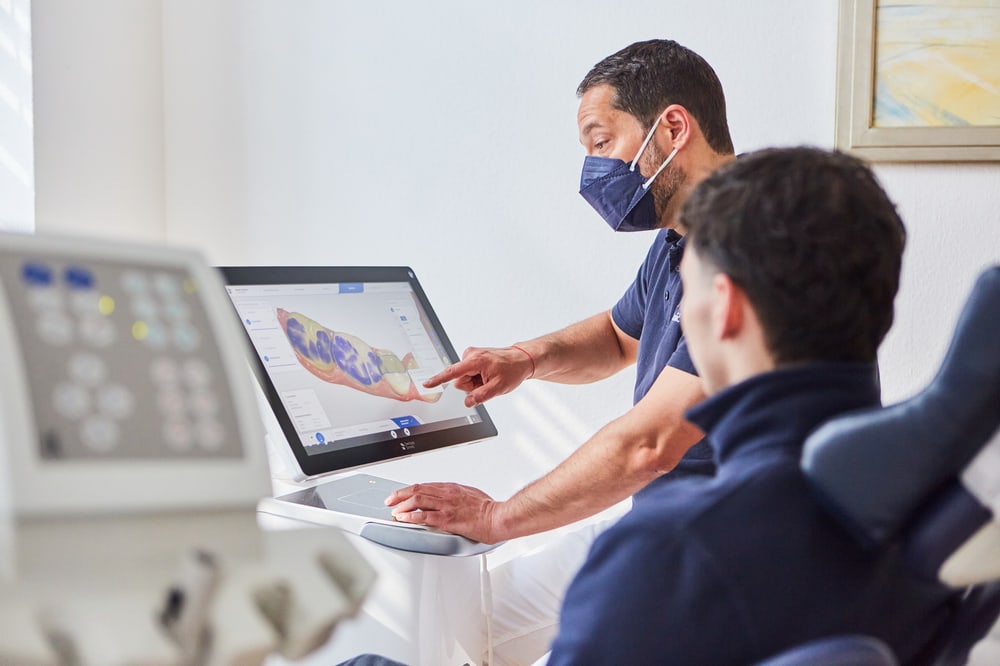 Zahnarzt erklärt einem Patienten den digitalen Scan