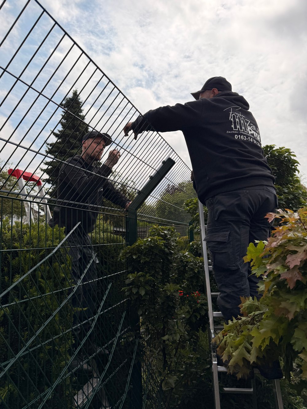 Zwei Monteure bauen einen Zaun
