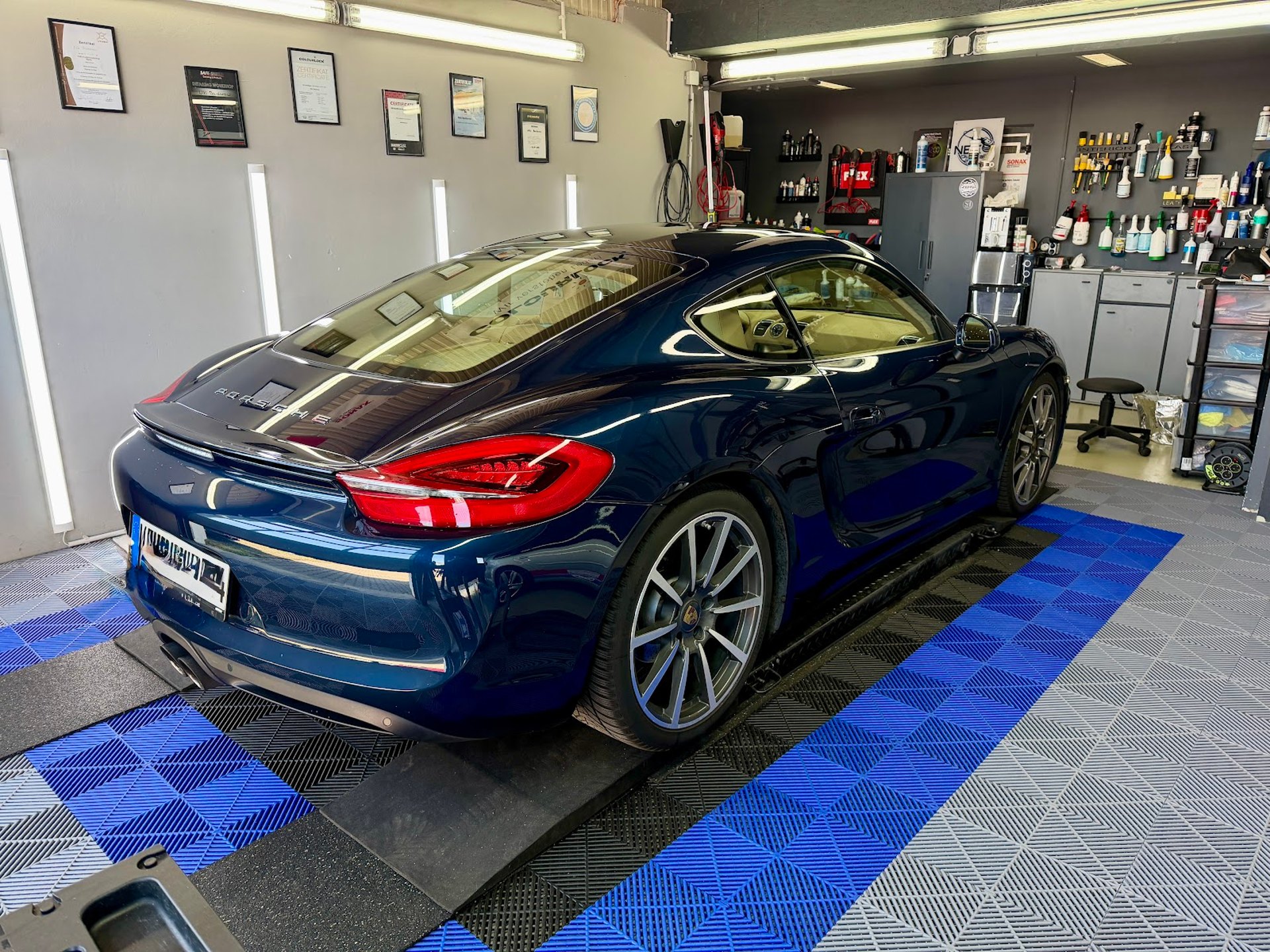 Glänzender blauer Porsche Cayman in der Werkstatt von NBK detailing in Kehl