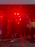 Menschen tanzen unter einem Dach, beleuchtet von starkem rotem Licht und Lasern.