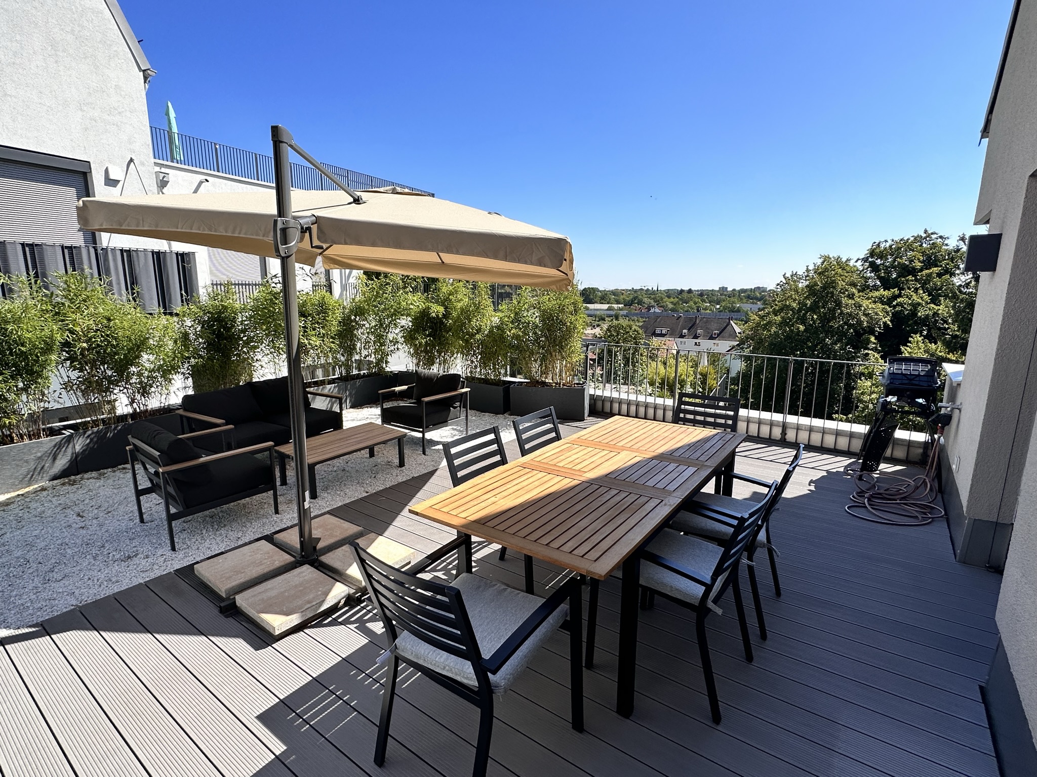 Die Terrasse mit langem Tisch und Sonnenschirm