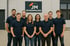 Neun Personen in dunkelblauen Poloshirts stehen vor einem Gebäude mit dem Logo "JM ENTRÜMPELUNG".