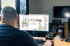 Ein Mann am Schreibtisch betrachtet einen detaillierten Geschossplan auf einem Computermonitor in einem Büro.