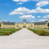 Barockes Karlsruher Schloss mit gelber Fassade, grünem Rasen und hellem Kiesweg unter blauem Himmel.