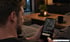 Ein Mann betrachtet auf seinem Smartphone eine App im dunklen Wohnzimmer mit Kerzenlicht im Hintergrund.
