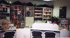 Büro mit Regalen voller Ordner und Zeitschriften, Empfangstresen und Stühlen.