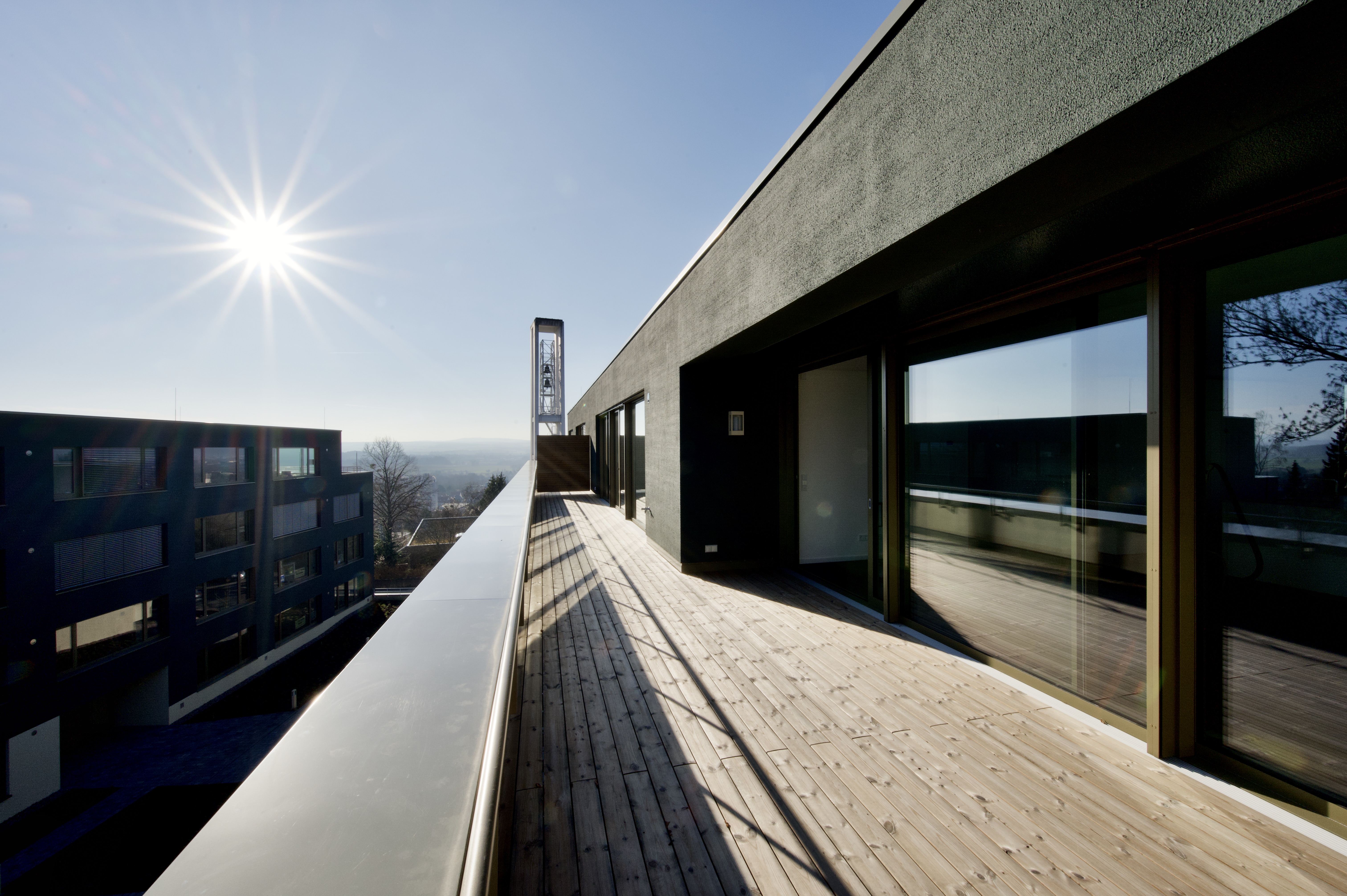 Großprojekt Himmelsruh – Holzterrasse am modernen Gebäude mit großer Glasfront