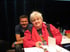 Markus Spenger mit blauem Hemd und Vera F. Birkenbihl mit roter Bluse sitzen lächelnd an einem Tisch.