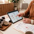 A person points to a body systems diagram on a tablet next to lab results and vitamin supplement bottles.