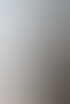 Ein Mann in einem weißen Hemd sitzt an einem schwarzen Tisch vor einem Fenster mit Hochhäusern.