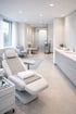 Heller, moderner Behandlungsraum mit Liege, Wartelounge und Waschbecken.
