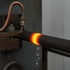 Ein glühendes Metallrohr wird von einer Maschine gekühlt, Wassertropfen fallen vom Rohr.