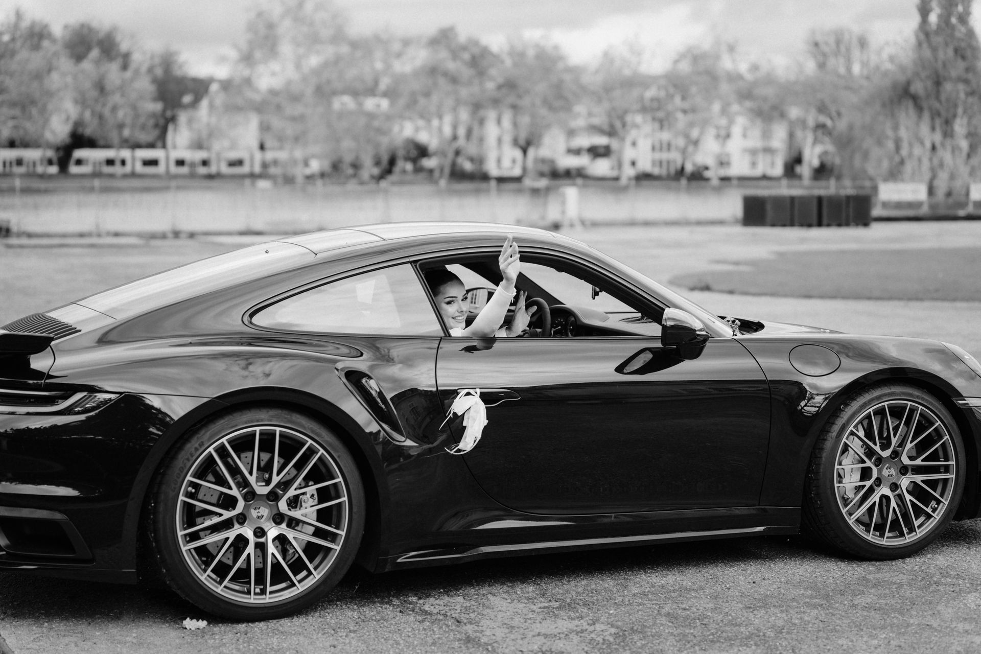Braut winkt aus dem abfahrenden Hochzeitsauto an Schloss Benrath in Düsseldorf, Schwarzweißaufnahme.