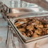 Gegrillte Hähnchenschenkel in einer silbernen Chafing-Dish auf einem Buffet.