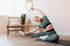 A woman doing seated yoga or stretching on a mat.