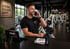 Ein lächelnder Mann in einem Fitnessstudio telefoniert an einem Tresen mit "club vital" Logo.