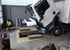 Ein weißer Lkw mit nach vorne gekipptem Fahrerhaus steht zur Wartung über einer Montagegrube in einer Werkstatt.