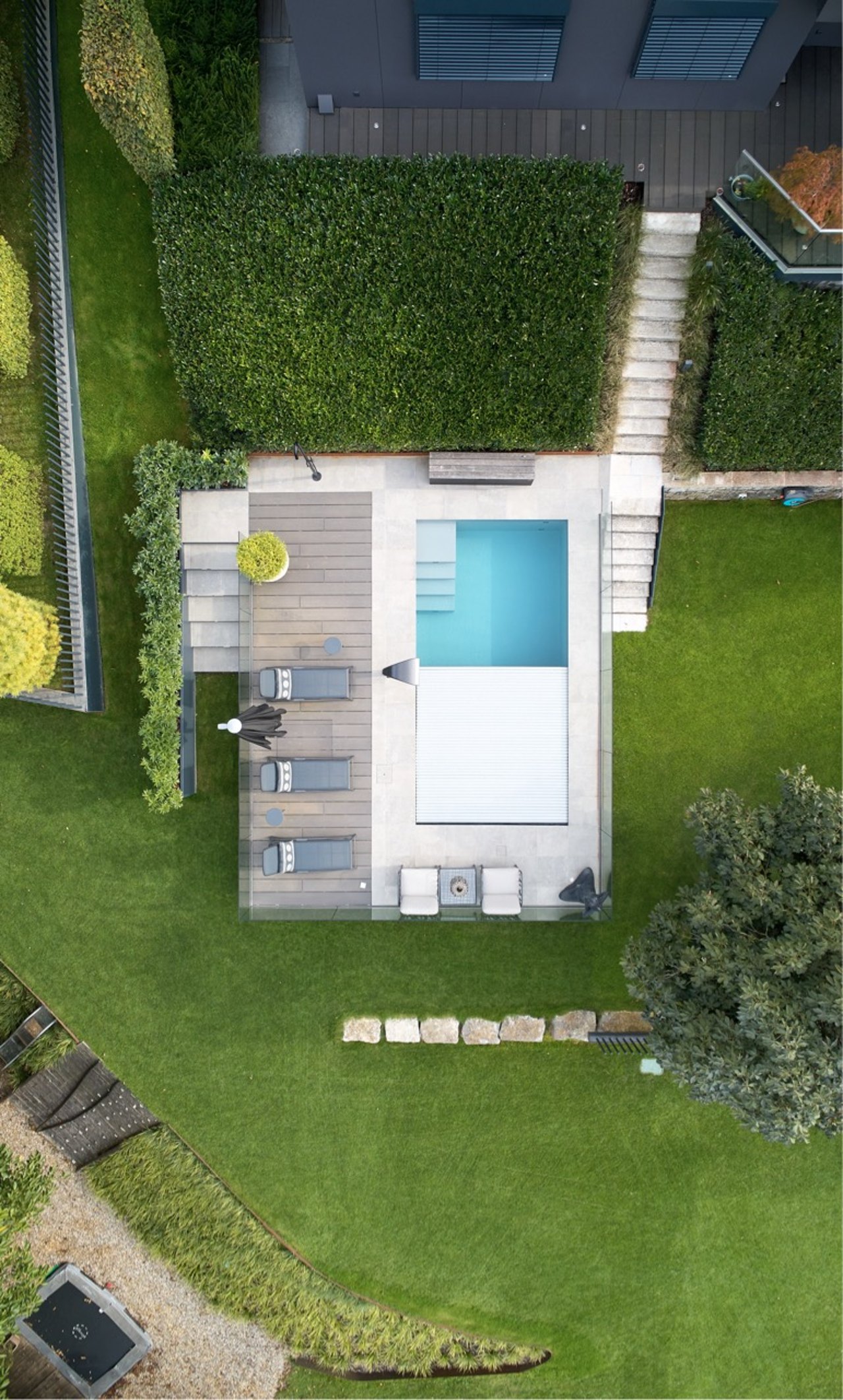 Garten mit Pool, Holzdeck und Sonnenliegen von oben