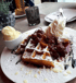 Waffeln mit Kirschen, Schlagsahne, Puderzucker, Mandelsplittern und einer Kugel Vanilleeis.