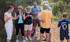 Eine Gruppe von Erwachsenen und ein Kind im Mbappe-Trikot machen eine Pause bei einer Wanderung im Grünen.