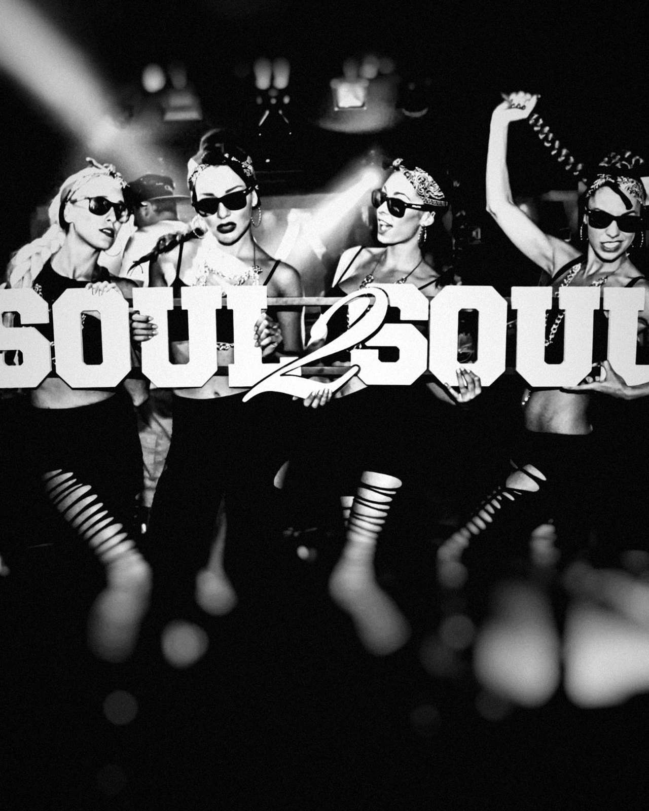 Vier Performerinnen mit Bandanas und Sonnenbrillen halten den Soul2Soul-Schriftzug