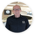 Ein lächelnder Mann mit Brille und schwarzem Mazda-Hemd steht in einem Autohaus.