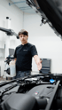 Automobilmechatroniker vor geöffneter Motorhaube