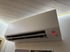 Graues Daikin Klimagerät an weißer Wand, mit roter Leuchtanzeige und LED-Lichtband an der Decke.