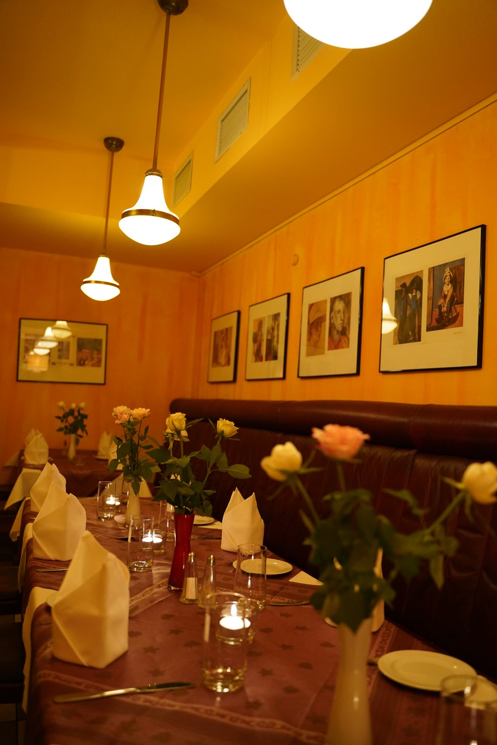 Eingedeckte Tische im Gastraum mit Rosen und Kerzenlicht