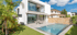 Modernes weißes Haus mit Pool, Terrasse, Esstisch und Palmen im Garten unter blauem Himmel.