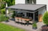 Eine moderne Terrassenüberdachung mit ausgefahrenem, grauem Sonnenschutz über einem Esstisch und Grill.