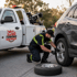 Towing Deltona roadside assistance technician replacing a flat tire on an SUV beside a tow truck at the roadside