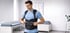 Man adjusting a black back brace with shoulder straps in a doctor's office.