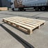 Helle Individuelle Holzpalette konfiguriert auf einem grauen Betonboden mit dunklen Fugen.