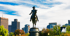 Equestrian statue of George Washington in Boston Public Garden with city skyline and blue sky.