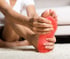 Person clutching foot with red sole, indicating neuropathy pain