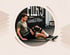 Ein Mann mit einer schwarzen Knieorthese sitzt auf dem Boden eines Fitnessstudios vor einer Wand mit der Aufschrift Training.
