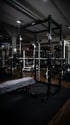 Schwarzes ATX Power Rack mit Hantelstange und Gewichten, davor eine Hantelbank mit Handtuch im Fitnessstudio.