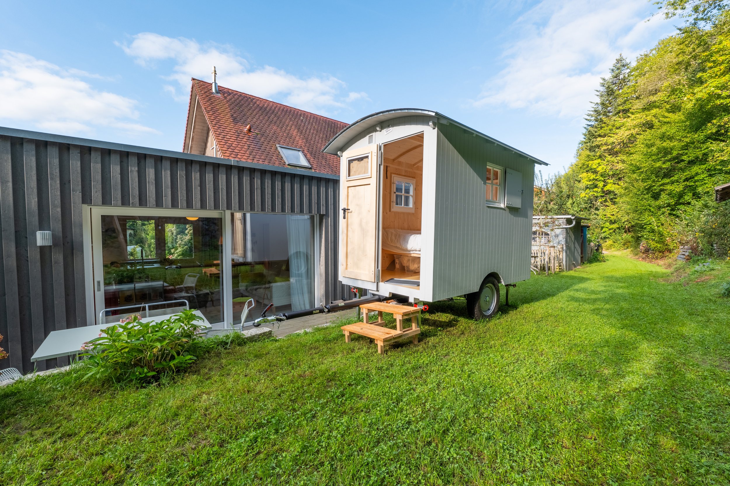 Garten mit Wiese, Zirkuswagen und Blick auf den Wald